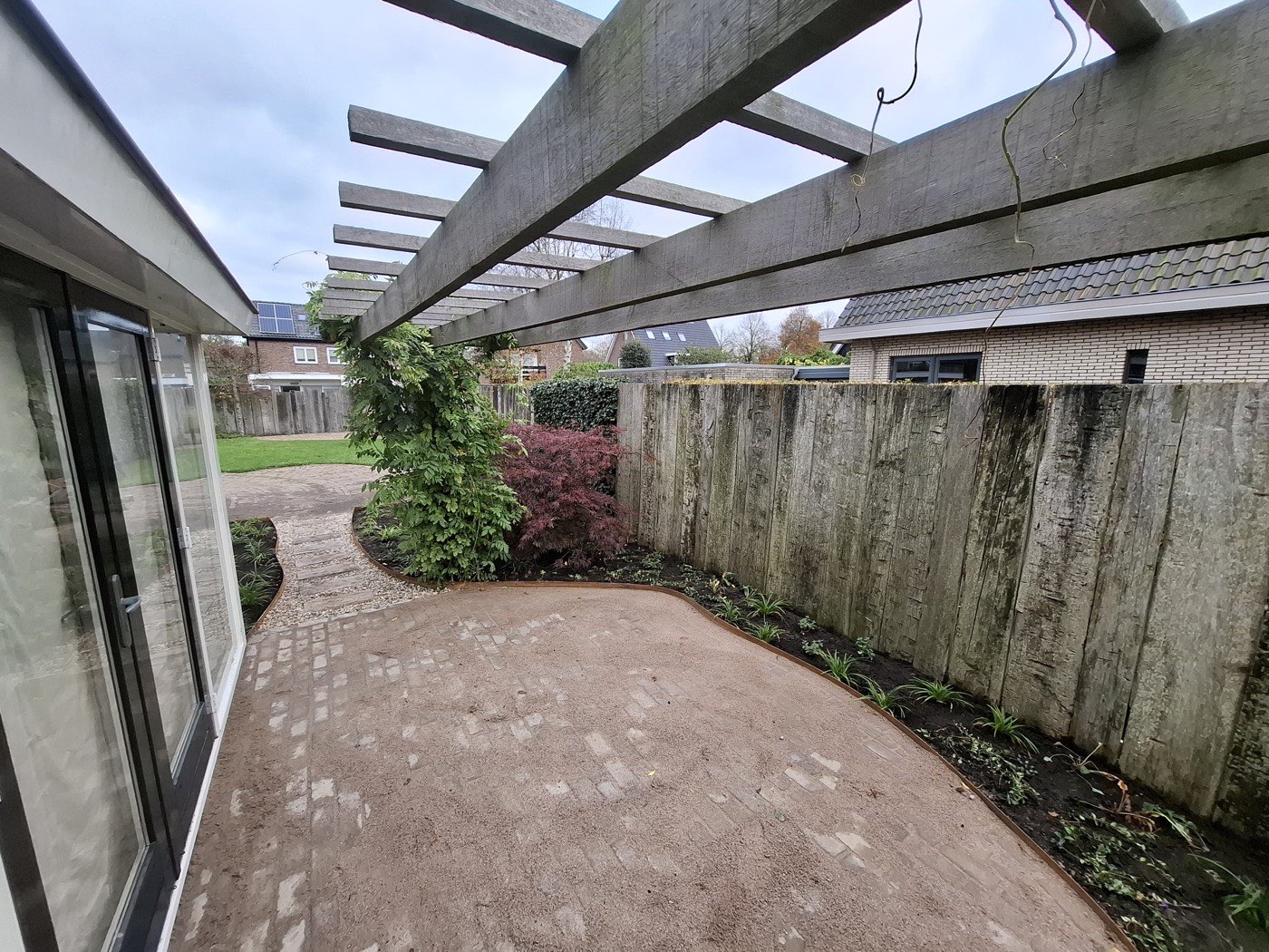Aangelegde tuin met pergola, rond terras en Japanse esdoorn