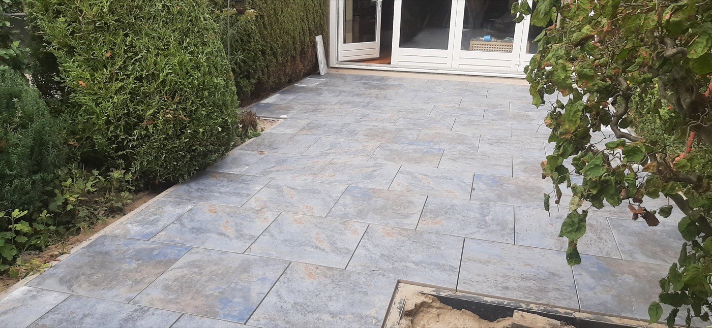 Terras van grote natuursteen tegels tegen de woning