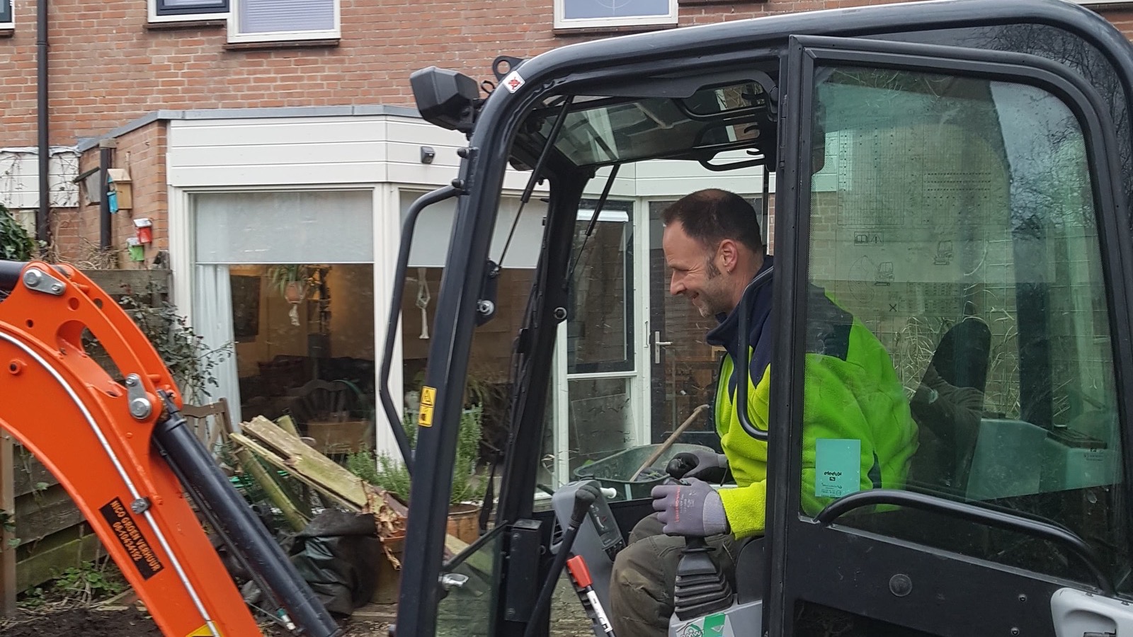 Joep Tijm aan het werk in de minigraver tijdens grondwerk voor een tuinrenovatie